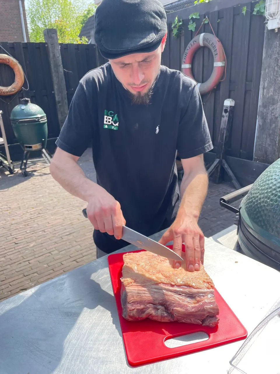 Mitch bereidt een stuk vlees voor naast de barbecue